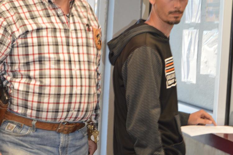 Sheriff Smith stands by as Tyler Frizzell is booked into jail.
