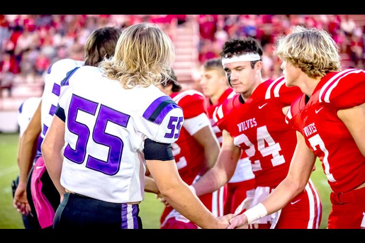 Walker Weston and the team captains shake hands before the game begins.