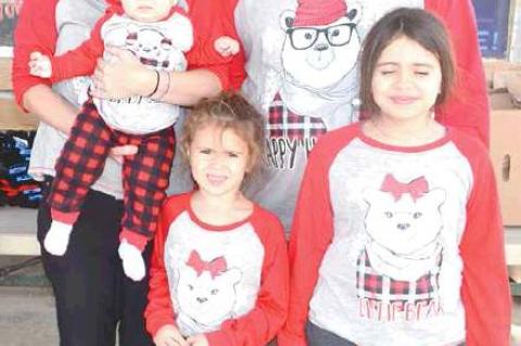 PATIENTLY WAITING ON SANTA CLAUS AT THE TUPELO CHRISTMAS CELEBRATION ARE (front) Rosalia Romero and Lilyana Romero. (back) Jessica Romero, holding baby Dahlia and Jose Romero.