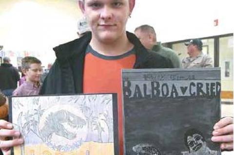 TUPELO ART SHOW — Freshman Logan Balthrop displays his artwork at Tupelo Schools’ first-ever art show. His drawings depict imagery related to “Rocky vs Creed” and “Jurassic Park,” both of which he is a fan.