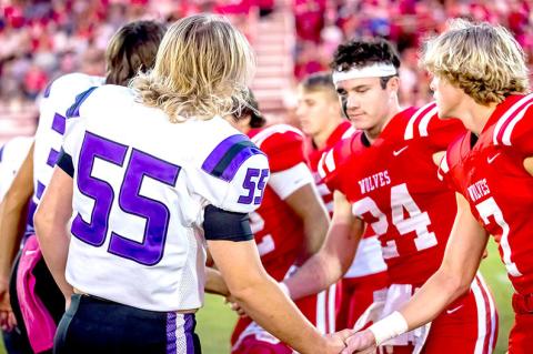 Walker Weston and the team captains shake hands before the game begins.