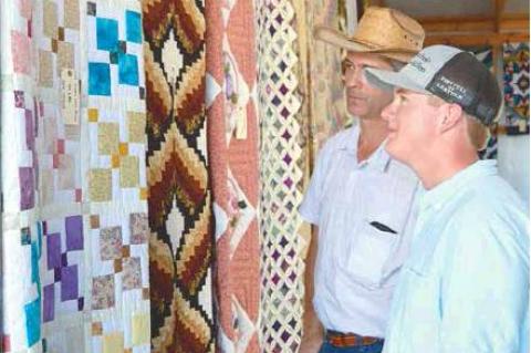 AMISH SCHOOL AUCTION— Robert Raber and his 15-year-old son Jeremiah look at the quilts about to be auctioned. Robert and his family are former residents of Clarita. They currently live in Fairland, OK.